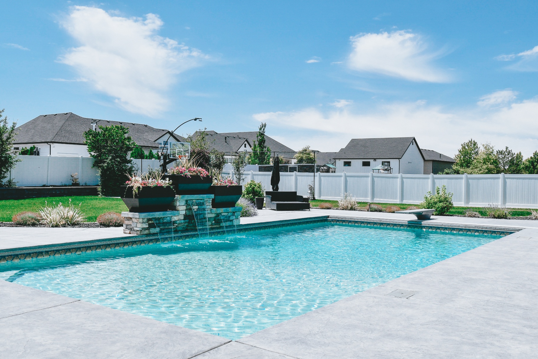 Syracuse Utah Backyard Pool Oasis with Stone Fountain — Barr Pool Builders Custom backyard swimming pool oasis with cascading stone fountain water feature in Syracuse, Utah by Barr Pool Builders